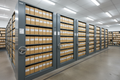 4-carriage mobile shelving system in archive room with carriages partially open showing labeled file boxes