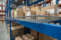 Wire deck panel on blue pallet rack beams in stocked warehouse with boxes on top
