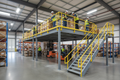 Completed mezzanine platform in active California warehouse with workers on upper deck and forklift below