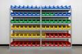 Fully stocked 5-shelf industrial bin shelving unit in clean parts room with color-organized bins
